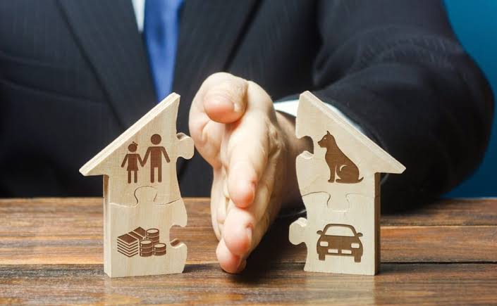 Hand dividing a wooden house model with family and property icons — property division in Ontario
